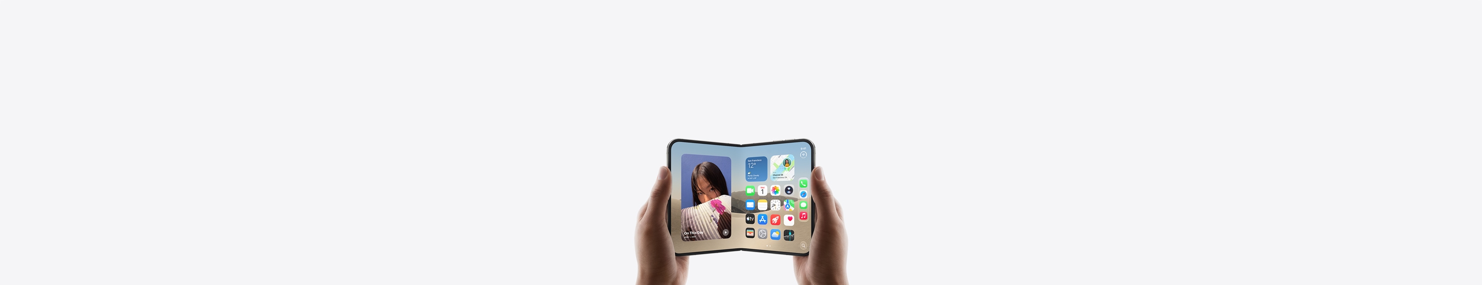 iPhone Duo, държан с две ръце хоризонтално, разгънат, вътрешният дисплей показва Home Screen