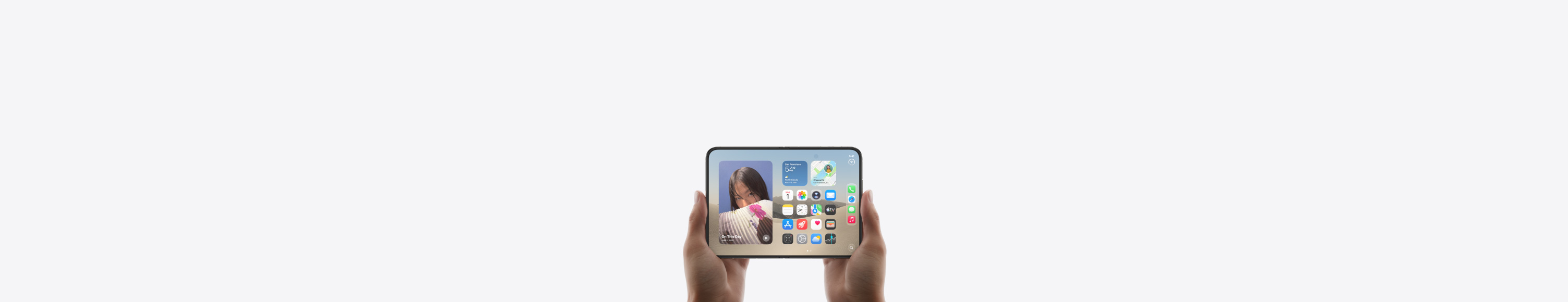 Otevřený iPhone Duo je otočený na šířku a drží ho dvě ruce, na vnitřním displeji je vidět plocha