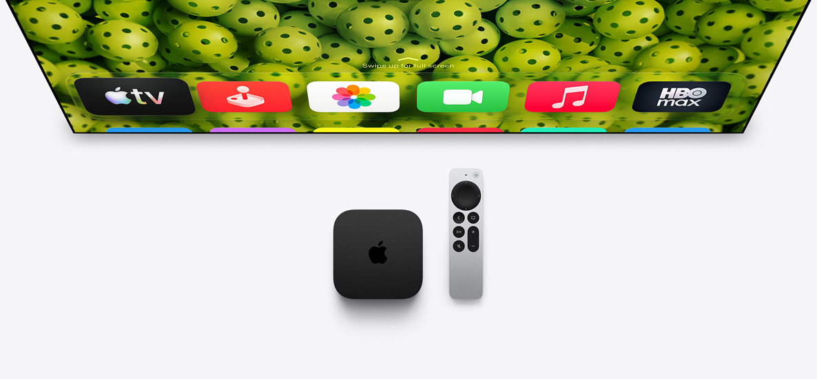 Une Apple TV 4K et une télécommande Siri Remote sous un écran de télévision, l’écran affiche la rangée supérieure des icônes d’apps de l’écran d’accueil sur un fond vert de pickleball