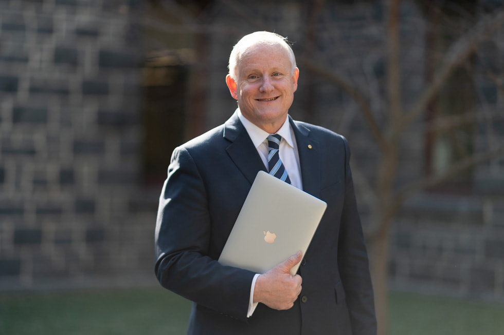 RMIT professor Calum Drummond on campus holding a MacBook Pro.