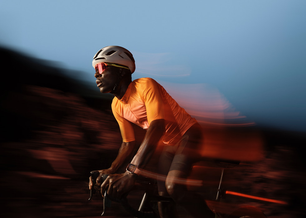 A cyclist is shown in motion wearing Apple Watch.