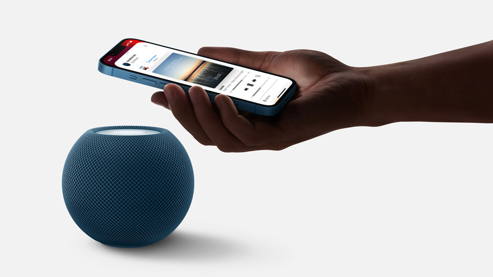 Bir kullanıcı iPhone’unu HomePod hoparlörün üzerinde tutuyor.