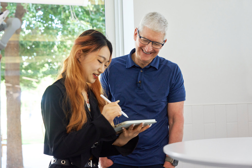 Foto de Tim Cook con un estudiante de programación que sostiene un iPad y un Apple Pencil.