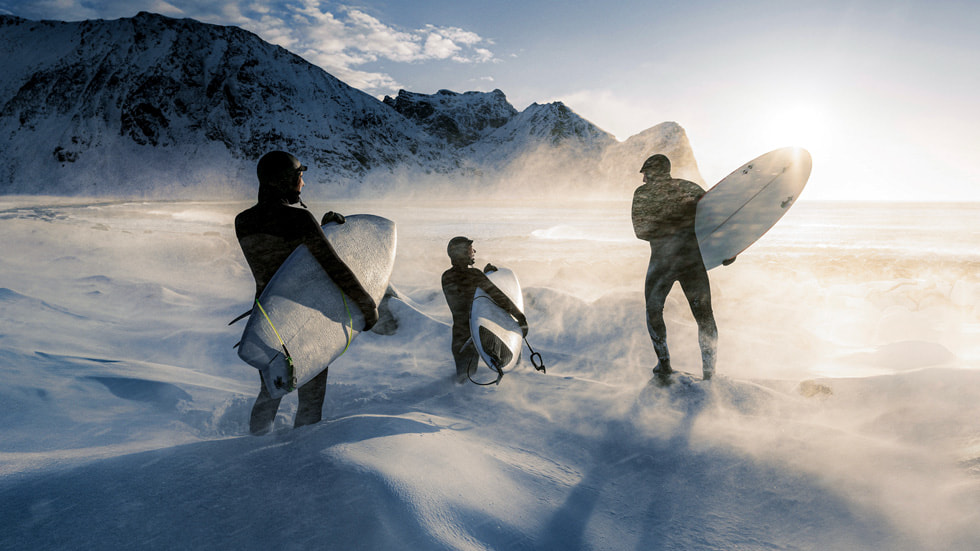 A group of surfers in snow approaching a beach in Norway.