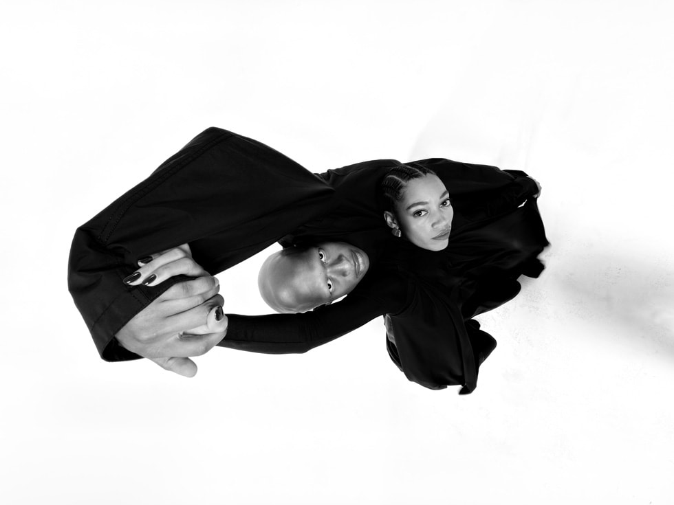 An overhead photo shot on iPhone 17 Pro shows two people with their arms raised.