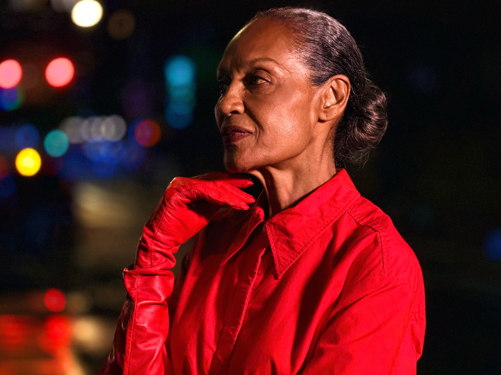 A low-light photo shot on iPhone 17 Pro features a person standing in a street at night.