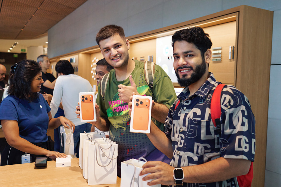 Two customers show off their cosmic orange new iPhone 17 Pro.