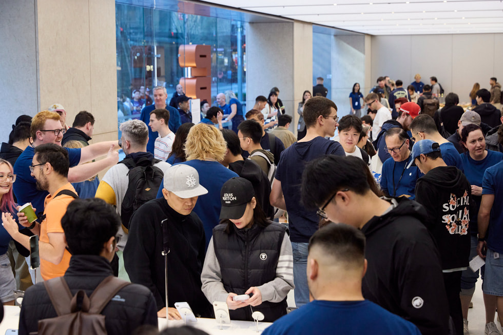 Apple team members assist excited customers inside the busy Apple Sydney store in Australia.
