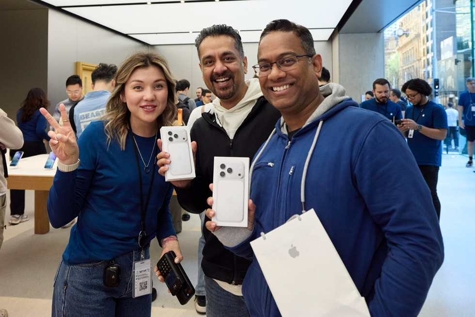 An Apple team member and two customers pose with their iPhone 17 Pro purchases at Apple Sydney in Australia.