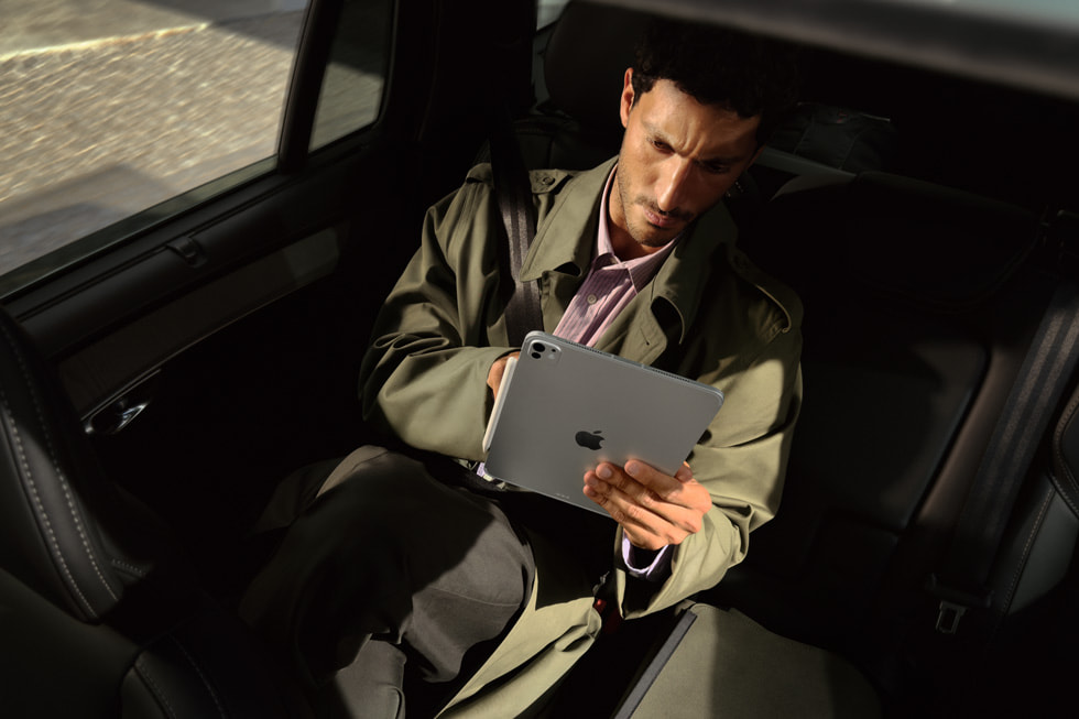A passenger in the back of a car looks at the new iPad Pro with M5 on the go.