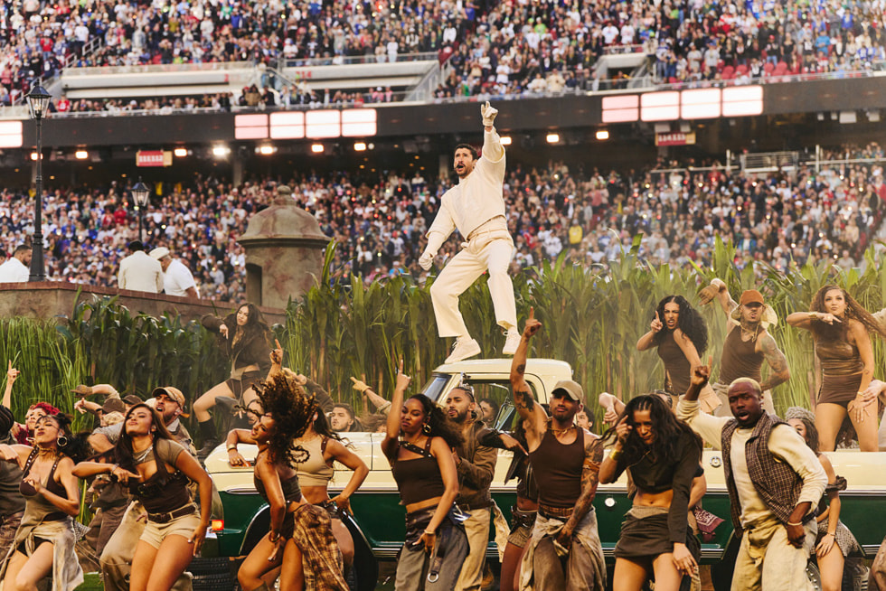 Bad Bunny staat boven op een auto tijdens de Apple Music Super Bowl LX Halftime Show.