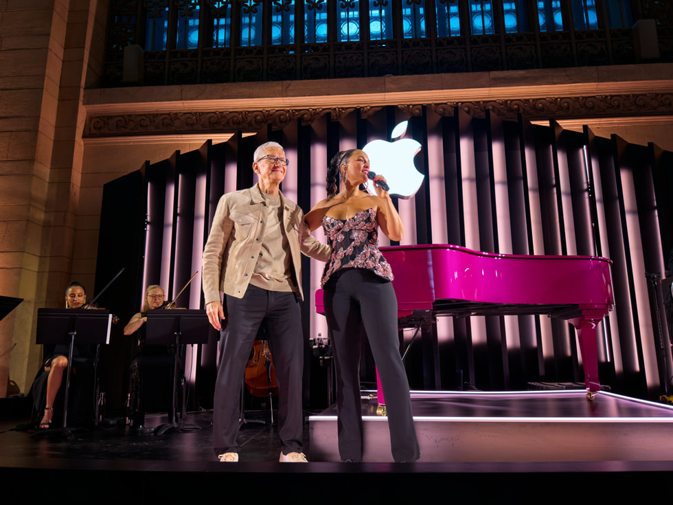 Tim Cook waves while standing onstage next to Alicia Keys.
