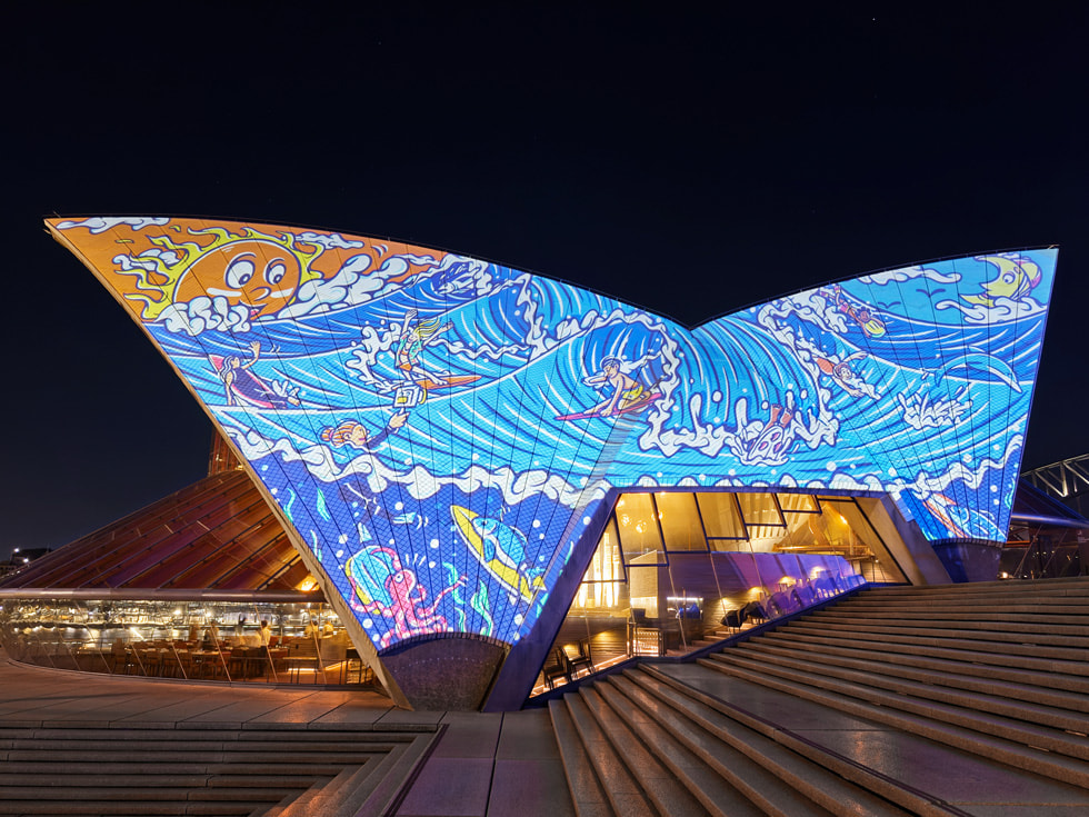 An artist’s Bennelong sails projection by Ryhia Dank shows a lizard amid colorful graphics.