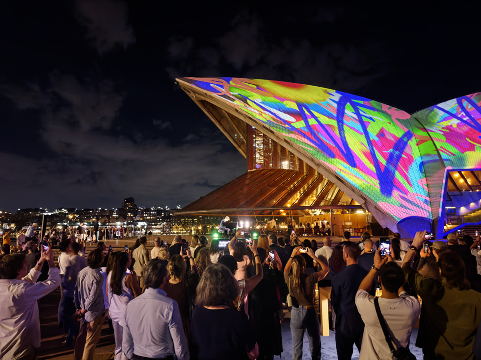 A crowd stands in front of Apple’s Bennelong sails projection installation.