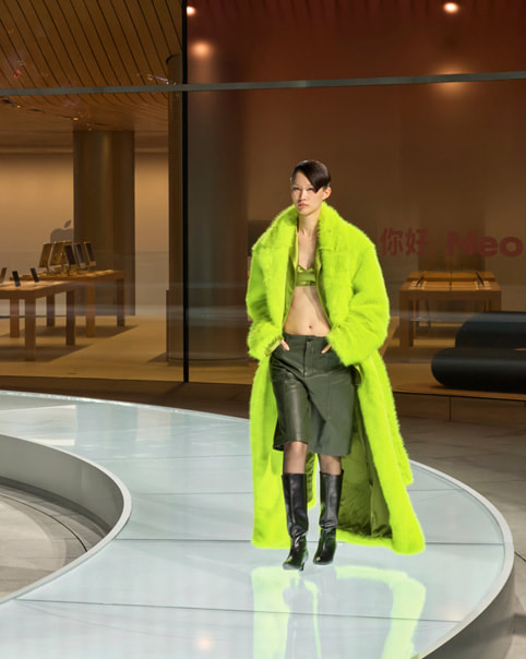 A model dressed in green walks a circular runway at Apple Jing’an.
