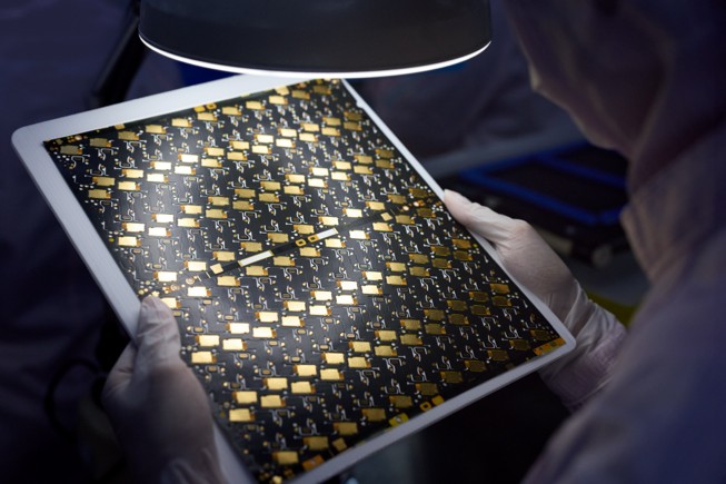 A worker holds a circuit board that features recycled gold plating.