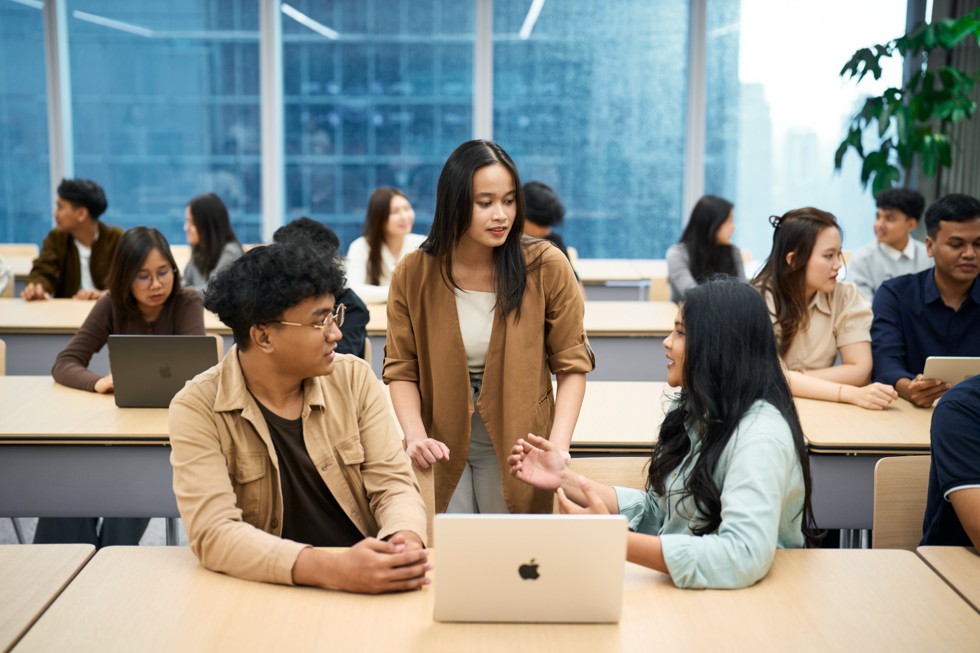 Peserta Apple Developer Institute di Indonesia berkolaborasi di meja modern menggunakan MacBook, dalam ruang kelas yang terang.