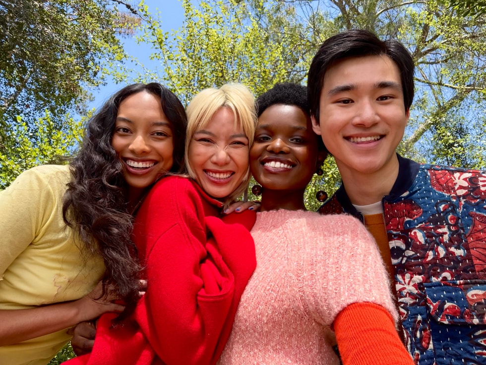 Bốn người mỉm cười và tạo dáng chụp ảnh selfie ngoài trời.