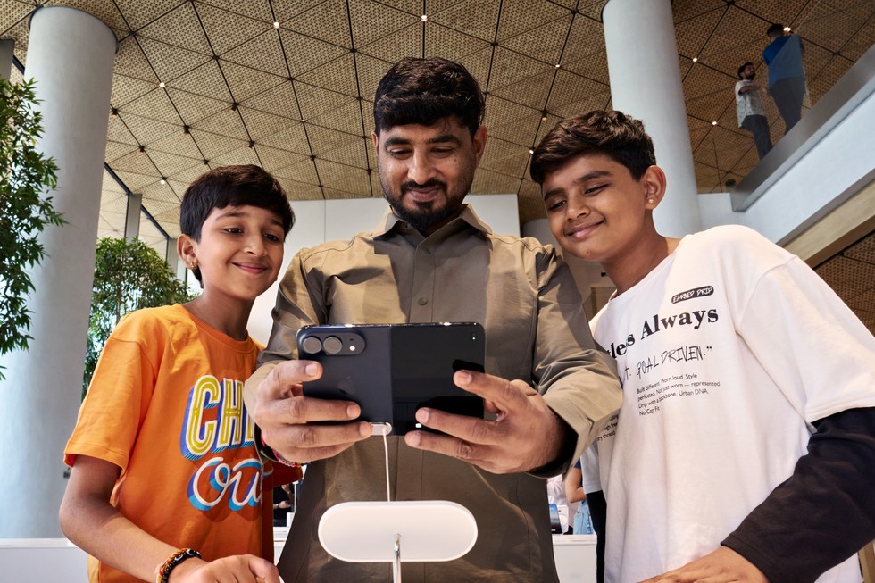At Apple BKC, a customer tries out iPhone Duo as two children watch.