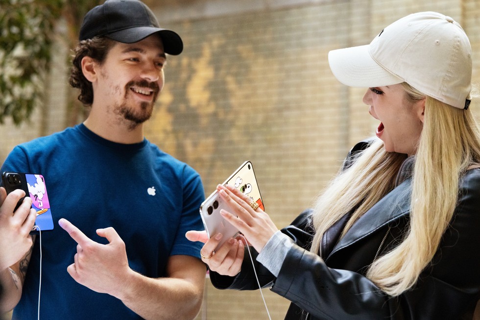 At Apple Covent Garden, an Apple team member points to a night sky iPhone Duo, while a customer holds up a star white iPhone Duo.
