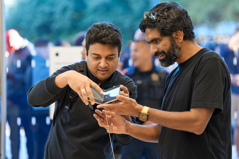 Two customers hold an iPhone Duo at the display table at Apple Domain NORTHSIDE.