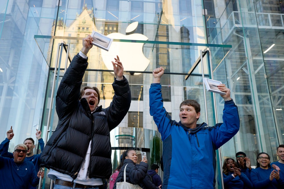 In front of Apple Fifth Avenue, two customers hold up their new iPhone Duo purchases.