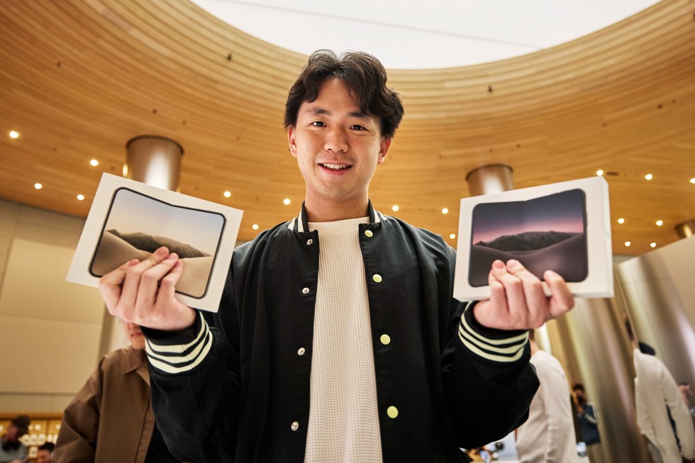 一位顧客在 Apple 靜安手拿兩盒 iPhone Duo，面露笑容。