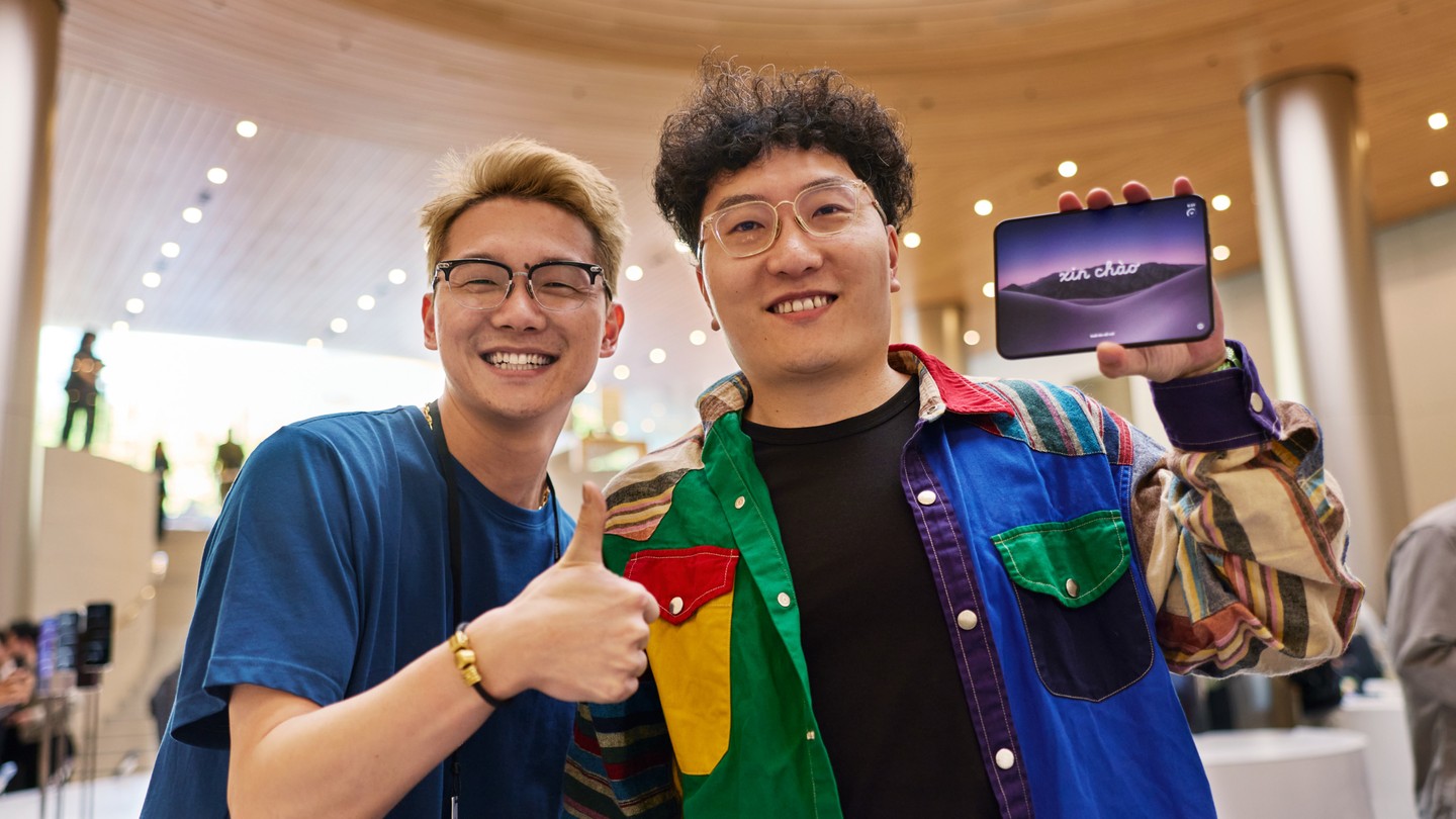在 Apple 靜安，一位顧客拿著 iPhone Duo，身旁的 Apple 團隊成員豎起大拇指。