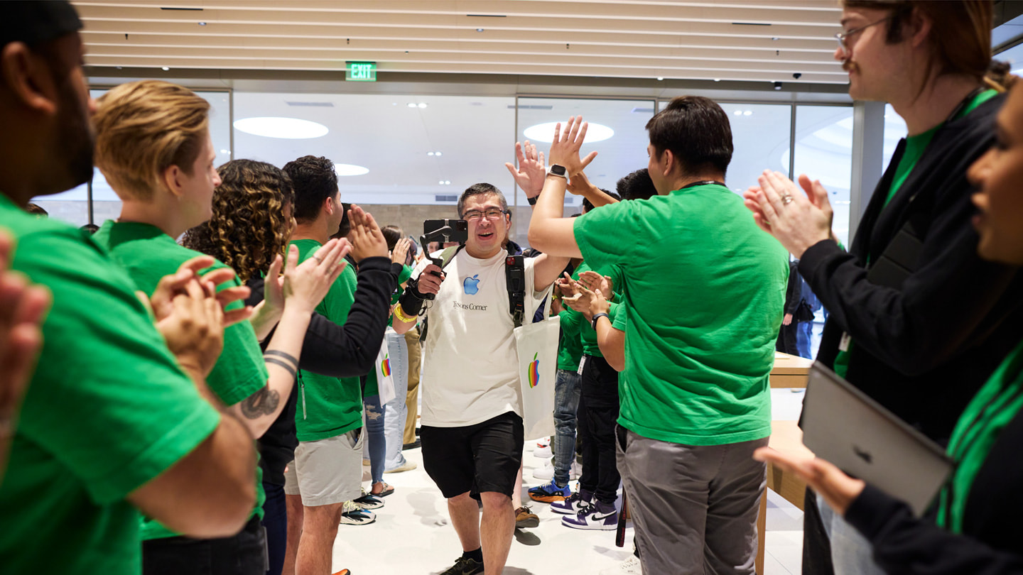 Clienti che entrano nell’Apple Tysons Corner mentre le persone del team battono le mani. 