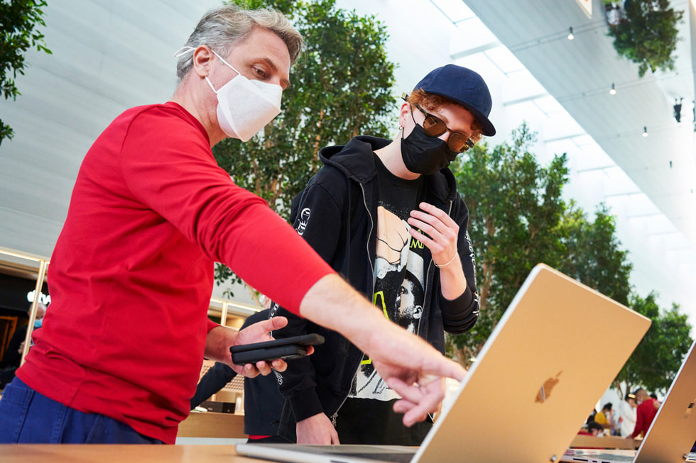 Apple The Grove team member showing a customer the new MacBook Pro.