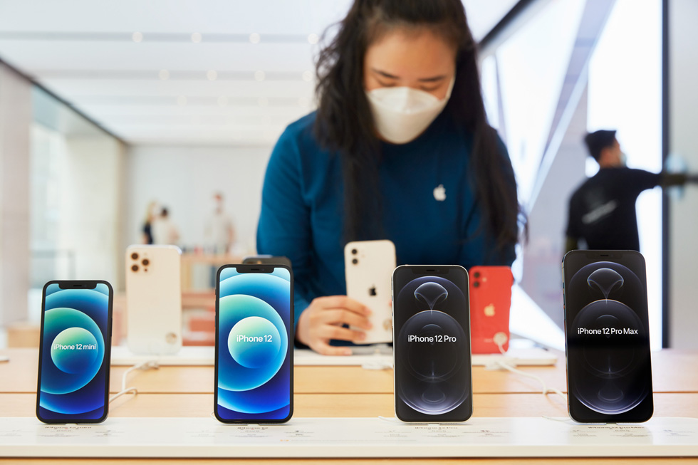 An Apple Sydney team member adjusts a display of iPhone 12 mini, iPhone 12, iPhone 12 Pro, and iPhone 12 Pro Max.