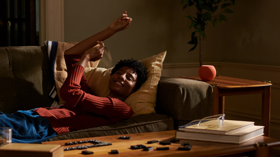 A man relaxes while listening to music on HomePod mini.