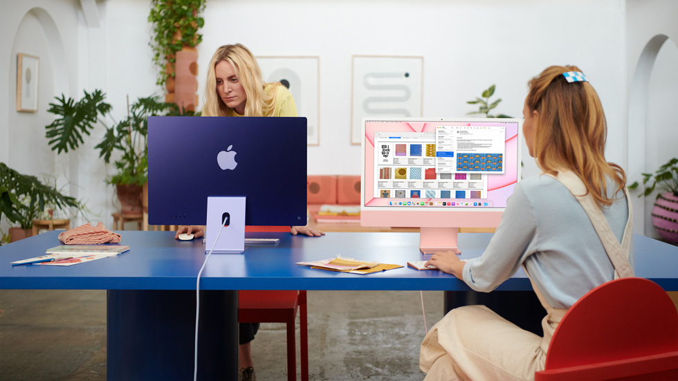 Two women use their iMac in a coworking space.