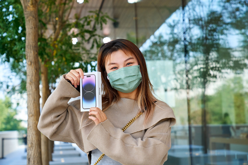 A woman holds her iPhone 14 Pro purchase outside of Apple Sanlitun.