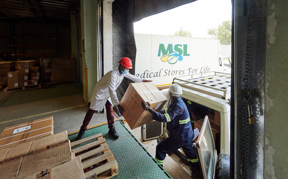 Workers in Zambia at a warehouse loading a box into a vehicle.