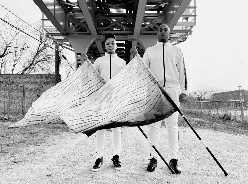 A man and woman, members of the South Shore Drill Team, hold flags.