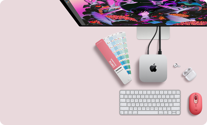 Mac mini, partea de sus, aluminiu argintiu, colțuri rotunjite, logo Apple negru lucios centrat, conectat prin cablu, monitorul Studio Display parțial vizibil de sus, căști AirPod 4, deschise, mostre de culoare Pantone, tastatură numerică și mouse