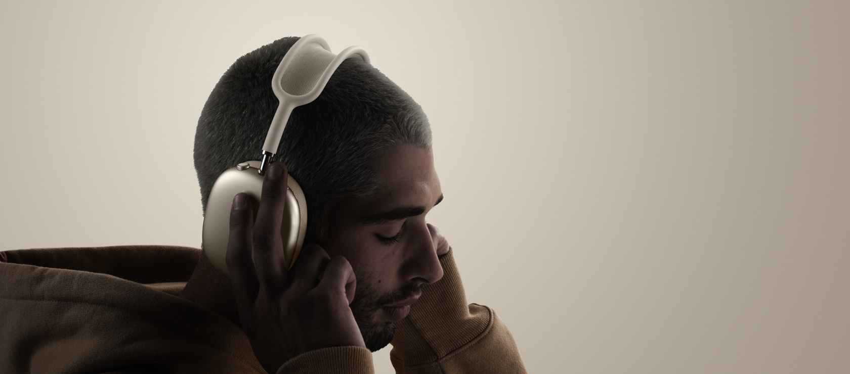Човек, носещ слушалки AirPods Max 2, страничен екстериор, докосва възглавничките за ушите