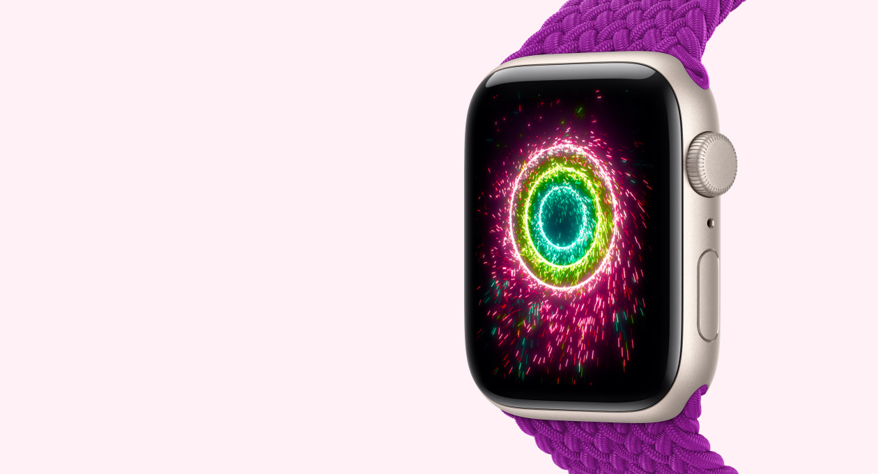 Apple Watch SE 3, starlight colour aluminium case connected to magenta colour Braided Solo Loop band, screen shows Activity rings styled as sparklers, pink, lime green, light blue concentric rings
