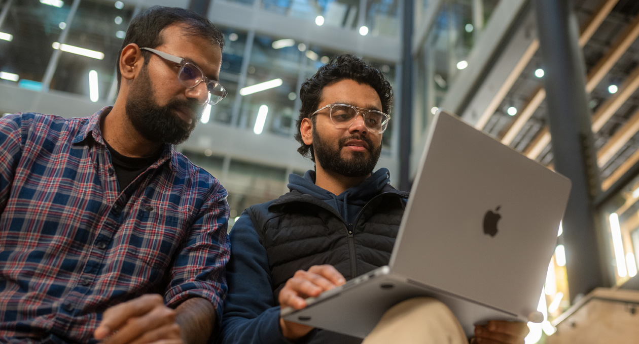 Dos hombres con lentes miran juntos una MacBook Pro