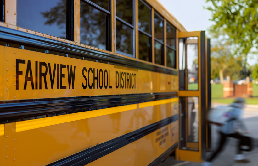Eine Nahaufnahme der Seite eines Schulbusses des Fairview School District, während ein Kind aus dem Bus steigt.