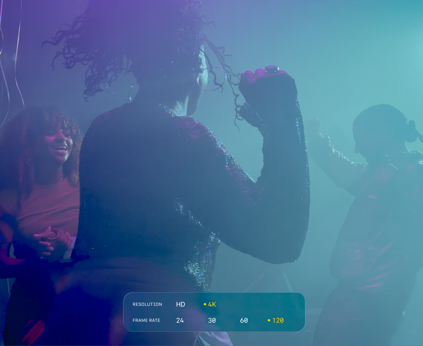A screen of three people dancing in low-light filming conditions shows the capabilties of 4K 120 fps Dolby Vision