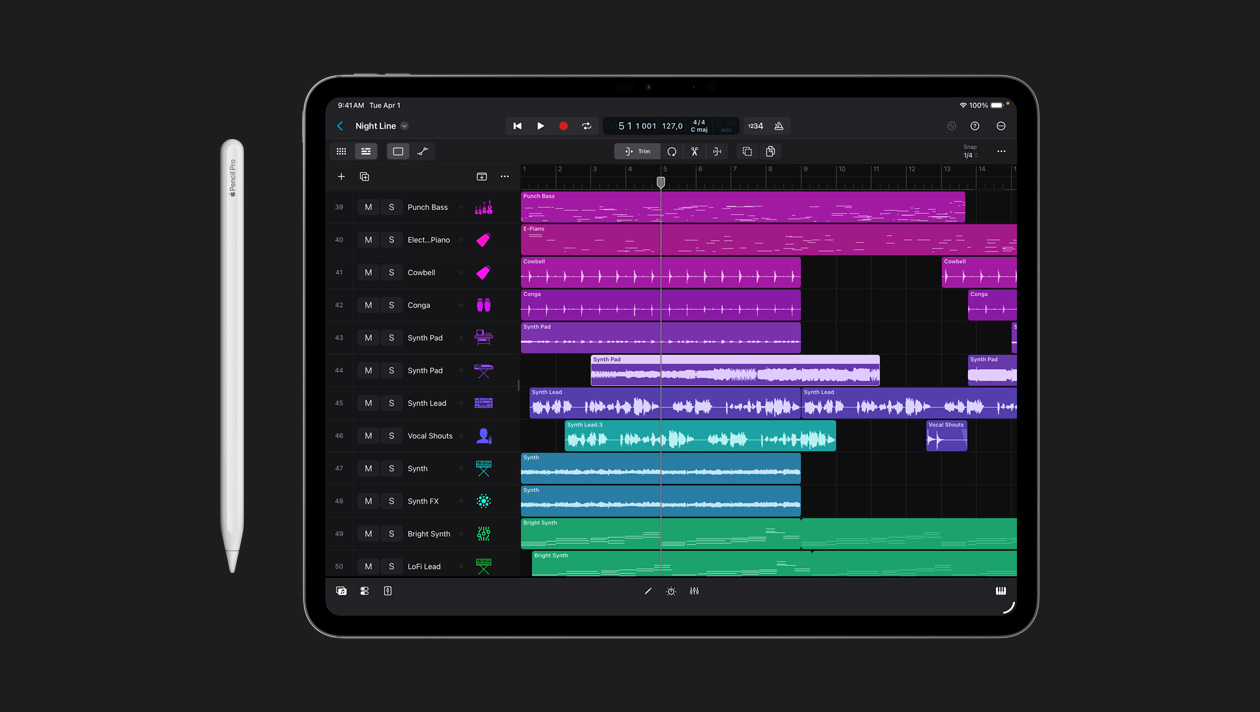 Layar iPad Pro 13 menampilkan ruang kerja Logic Pro, daftar berbagai instrumen di panel kiri dan gelombang suaranya dalam berbagai warna di kanan, Apple Pencil di sebelah kiri perangkat