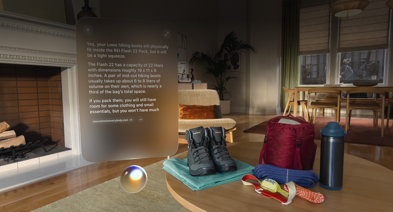Apple Vision Pro 화면. Siri 위에는 등산화가 배낭에 들어가는지 묻는 대화창이 표시되어 있으며, 대화창은 등산화 한 켤레와 다른 아웃도어 장비의 왼쪽에 떠 있습니다.