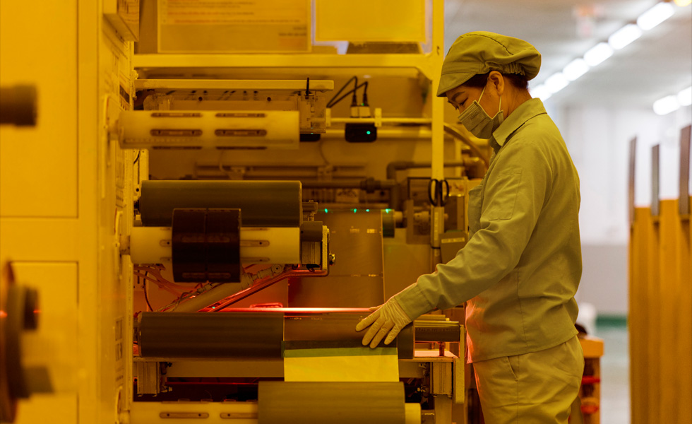 En uniformeret medarbejder med mundbind trykker på knapper på produktionsudstyr
